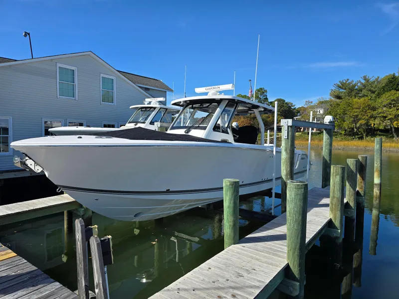 The Image of 2025 Pursuit S 328 boat docked at a marina under clear blue skies. - 0