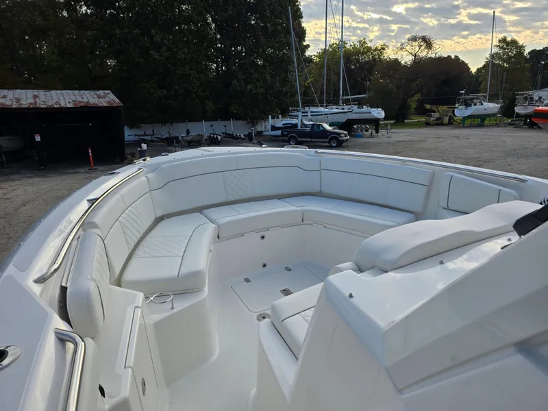 Slide: The Image of 2025 Pursuit S 328 boat with spacious white seating, docked outdoors under a cloudy sky. - 17