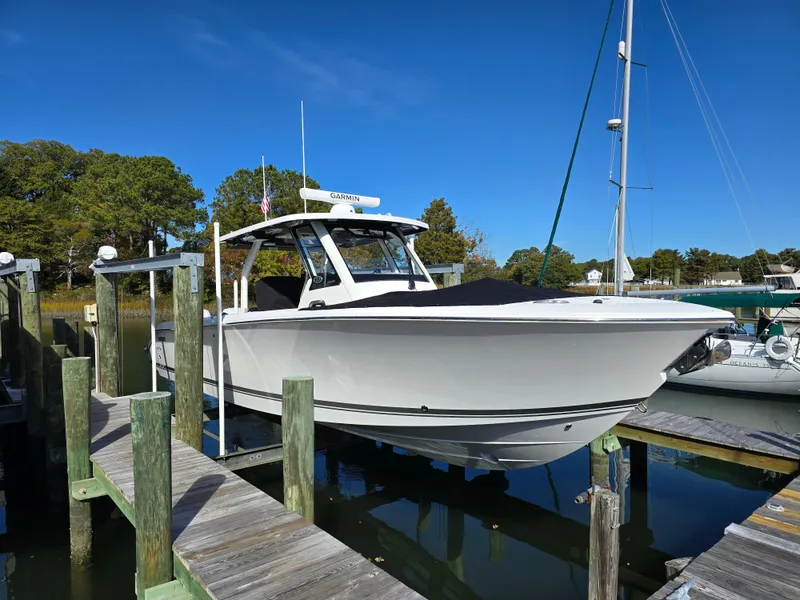 Slide: The Image of 2025 Pursuit S 328 boat docked in a marina under clear blue skies. - 2