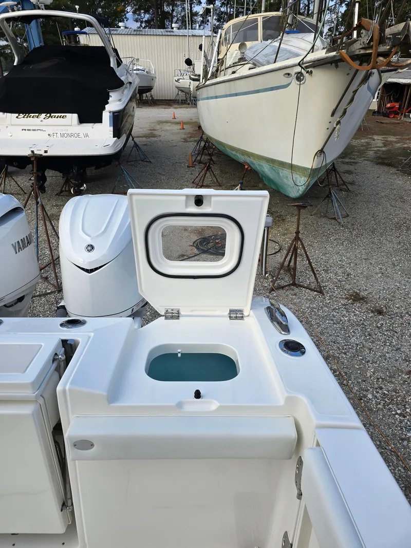 Slide: The Image of 2025 Pursuit S 328 boat with open hatch, showcasing storage compartment, in a marina setting. - 8