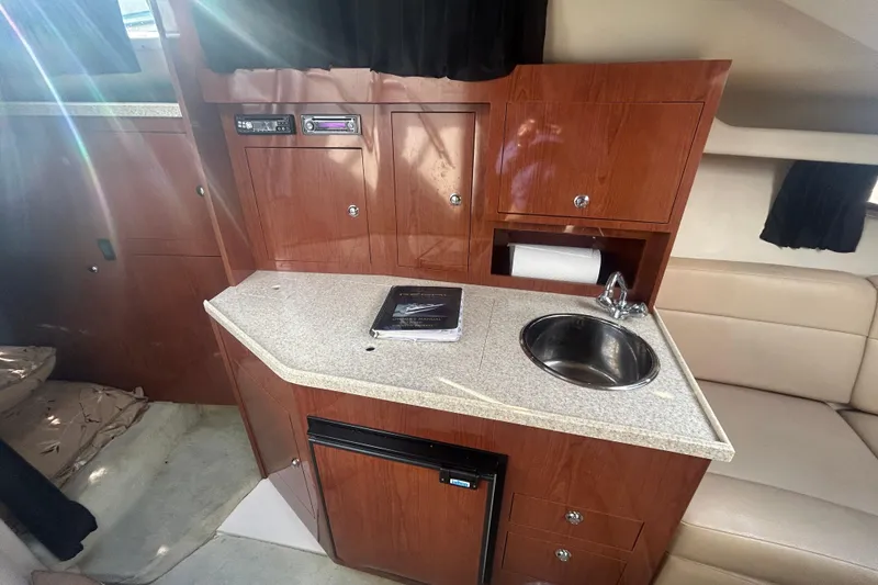 Slide: The Image of 2007 Regal 3060 Express Cruiser interior with kitchenette, sink, and wooden cabinetry. - 10