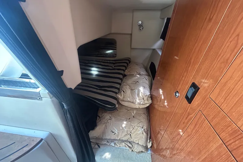 Slide: The Image of 2007 Regal 3060 Express Cruiser cabin interior with striped bedding and wooden cabinetry. - 7