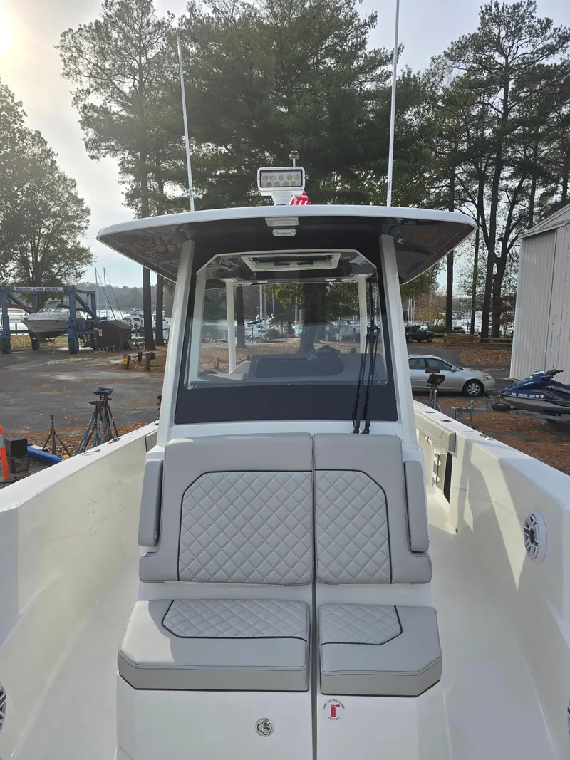 Slide: The Image of 2025 Pursuit S 288 boat with cushioned seating, docked near trees and parked cars. - 15