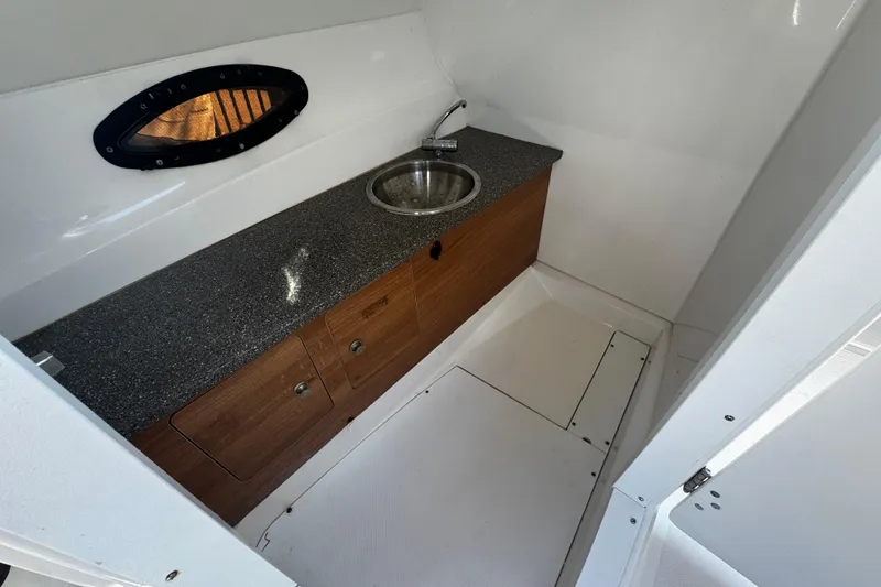 Slide: The Image of 2019 Hurricane SunDeck 2690 OB interior with sink and wooden cabinetry. - 13