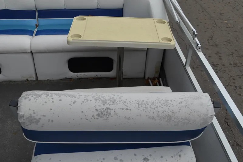 Slide: The Image of 1992 Manitou SPORT boat interior with white and blue seating, small table, and metal railing. - 11
