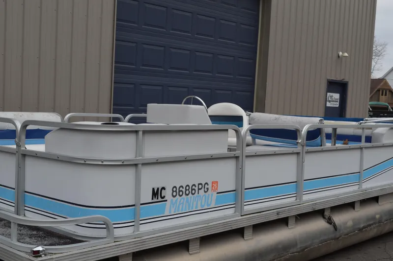 Slide: The Image of 1992 Manitou SPORT pontoon boat with blue accents, parked near a garage. - 21