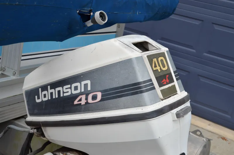 Slide: The Image of 1992 Manitou SPORT boat with Johnson 40 outboard motor, blue cover, and garage background. - 23