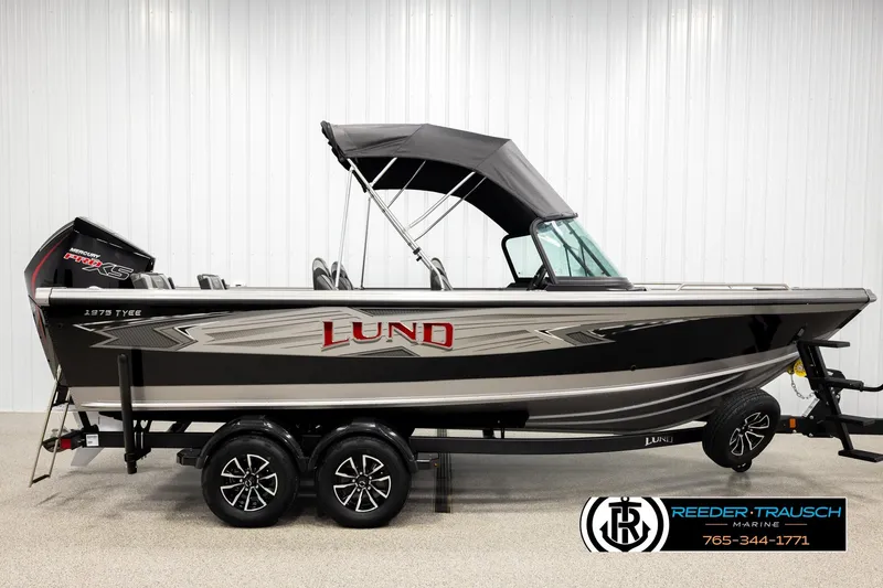Slide: The Image of 2026 Lund 1975 Tyee boat with black canopy and trailer in showroom. - 4