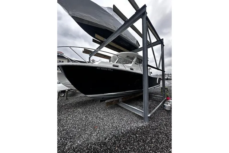 Slide: The Image of 2021 NorthCoast 315 Cabin boat stored on a metal rack, overcast sky. - 5