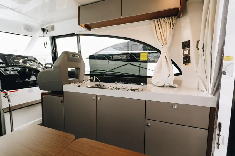 Slide: The Image of Interior of 2026 Beneteau Antares 11 Fly yacht, featuring helm and kitchenette. - 13