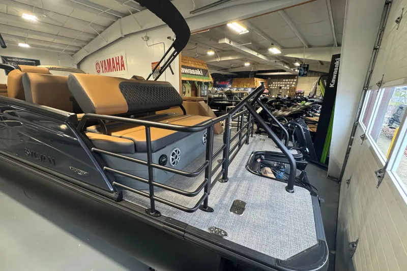 Slide: The Image of 2026 Sylvan L3 DLZ pontoon boat displayed in a showroom with tan seating. - 8