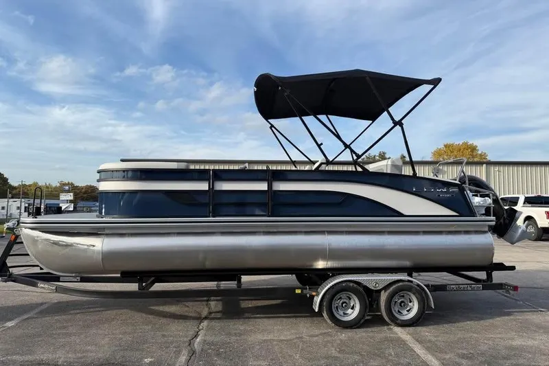 The Image of 2026 Lowe SS 230 DV pontoon boat with canopy on trailer, parked outdoors. - 0