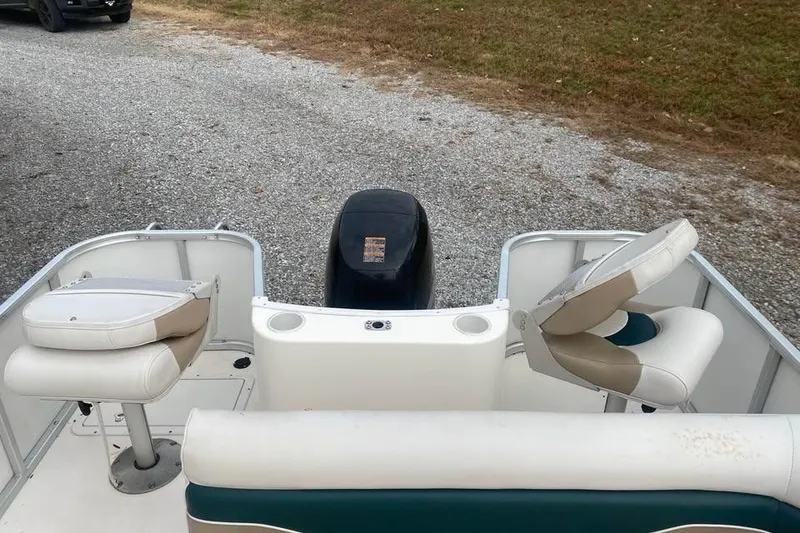 Slide: The Image of 2005 Hurricane FunDeck 196 FF boat interior with seating and motor, parked on gravel. - 9