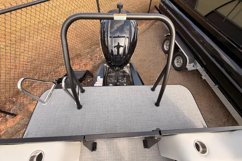 Slide: The Image of 2026 Veranda Vista Sport VS25RC boat with motor and railing, parked near a fence. - 24