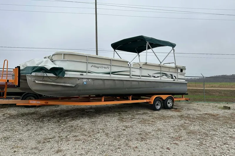 The Image of 2004 PlayCraft Powertoon 26 pontoon boat on trailer, parked outdoors. - 1