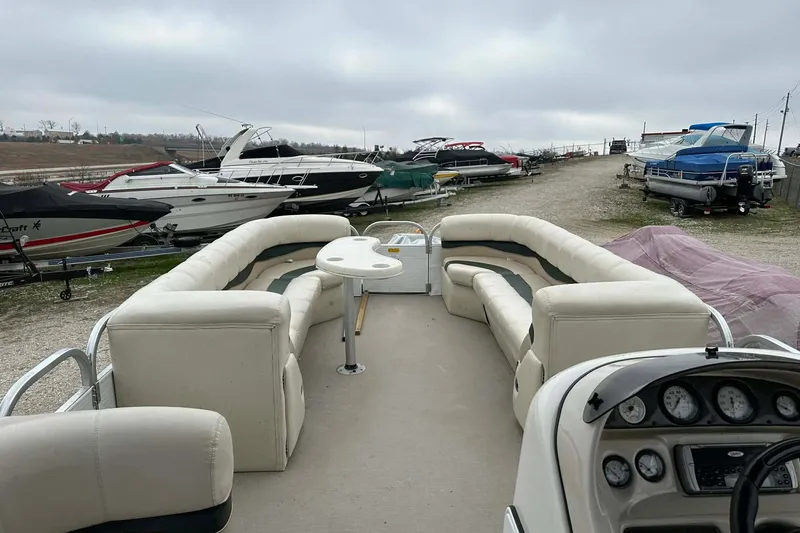 Slide: The Image of 2004 PlayCraft Powertoon 26 pontoon boat with spacious seating, docked among other boats. - 9