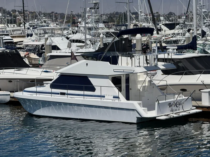 The Image of 2001 Zeta Flybridge Power Catamaran docked in a marina, surrounded by other boats. - 0