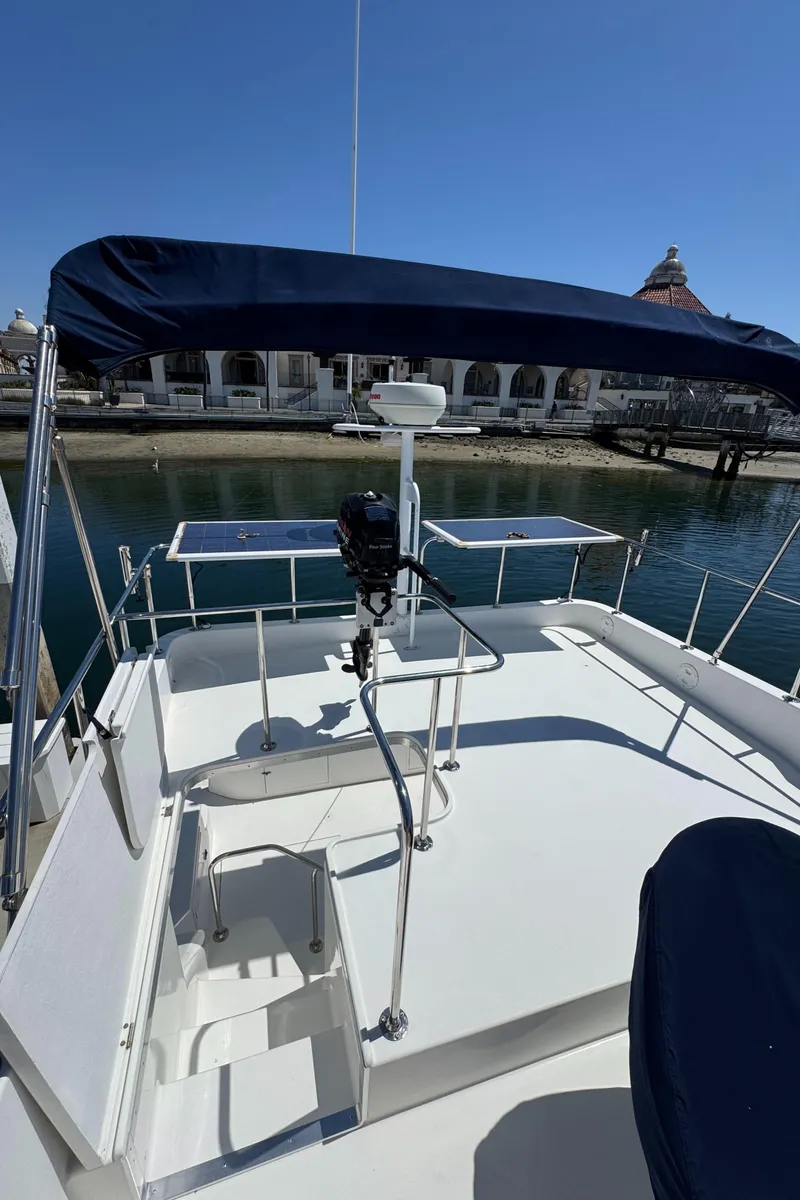 Slide: The Image of 2001 Zeta Flybridge Power Catamaran with blue canopy, docked near waterfront buildings. - 33