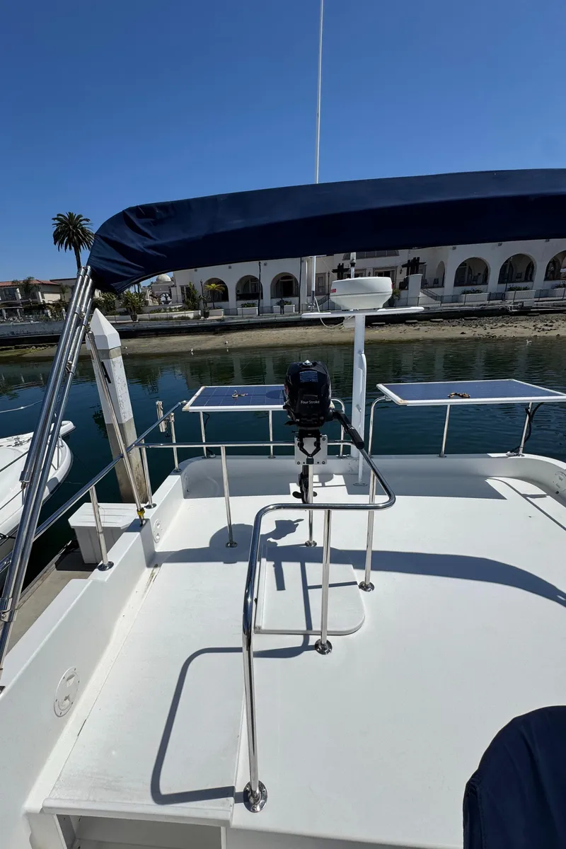 Slide: The Image of 2001 Zeta Flybridge Power Catamaran with blue canopy, docked near waterfront buildings. - 41