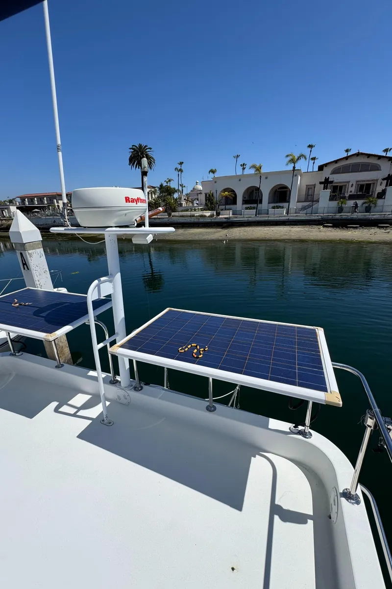 Slide: The Image of 2001 Zeta Flybridge Power Catamaran with solar panels, docked near waterfront homes. - 43