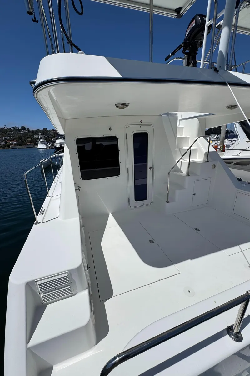 Slide: The Image of 2001 Zeta Flybridge Power Catamaran, spacious deck, sleek design, docked on calm water. - 49
