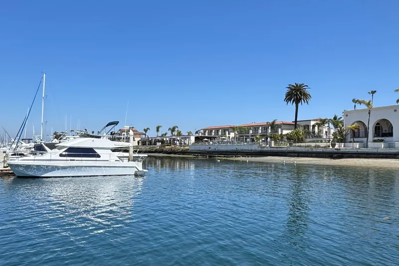 Slide: The Image of Zeta Flybridge Power Catamaran 2001 docked in a sunny marina with palm trees. - 7