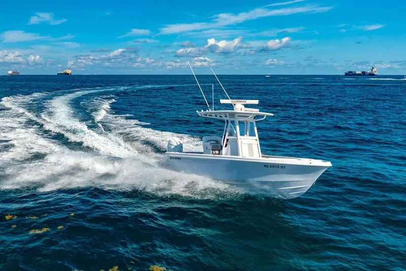 Slide: The Image of 2024 Reef Runner 230 Open boat cruising on open ocean under clear blue sky. - 25