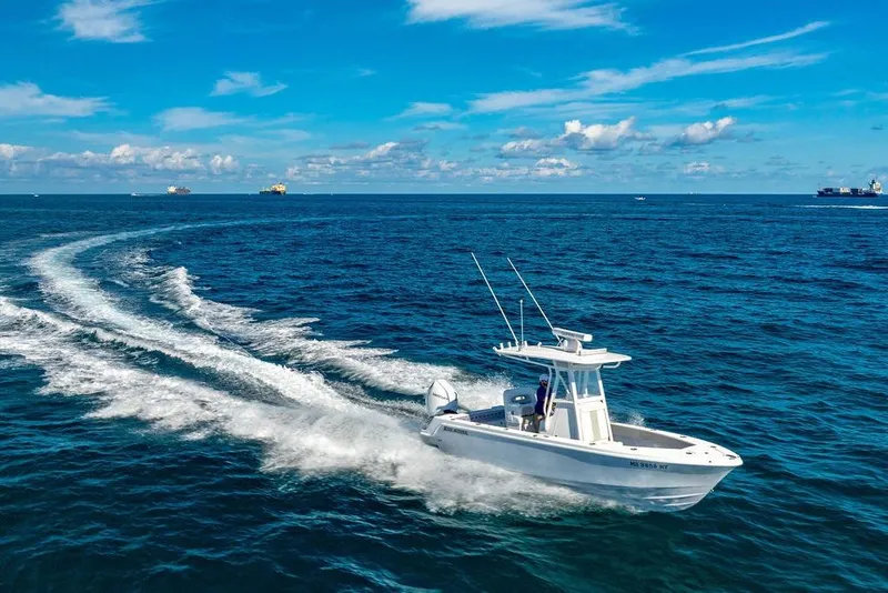 Slide: The Image of 2024 Reef Runner 230 Open boat cruising on open ocean under clear blue sky. - 26