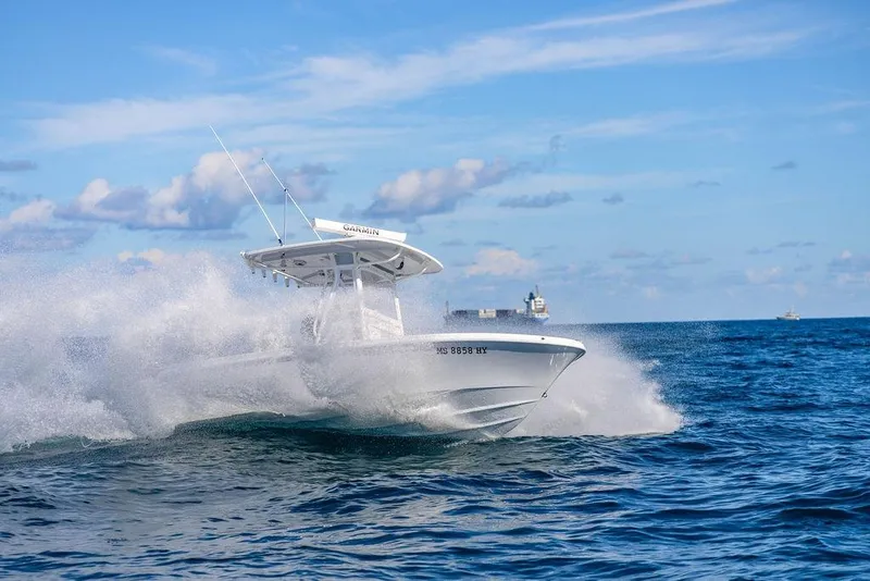 Slide: The Image of 2024 Reef Runner 230 Open boat cruising on ocean waves under a clear blue sky. - 39