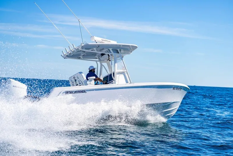 Slide: The Image of 2024 Reef Runner 230 Open boat cruising on open water under clear blue skies. - 48