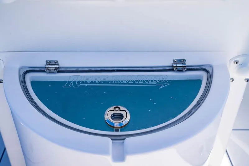 Slide: The Image of 2024 Reef Runner 230 Open boat compartment with logo and latch. - 55