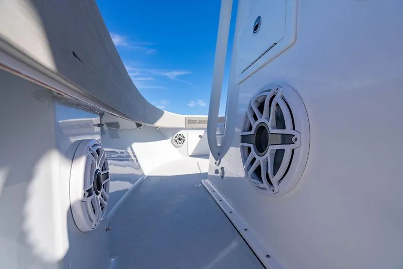 Slide: The Image of 2024 Reef Runner 230 Open boat interior with speakers, showcasing sleek design under blue sky. - 77