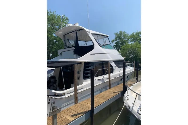 Slide: The Image of 2004 Carver 460 Voyager yacht docked at marina under clear blue sky. - 2