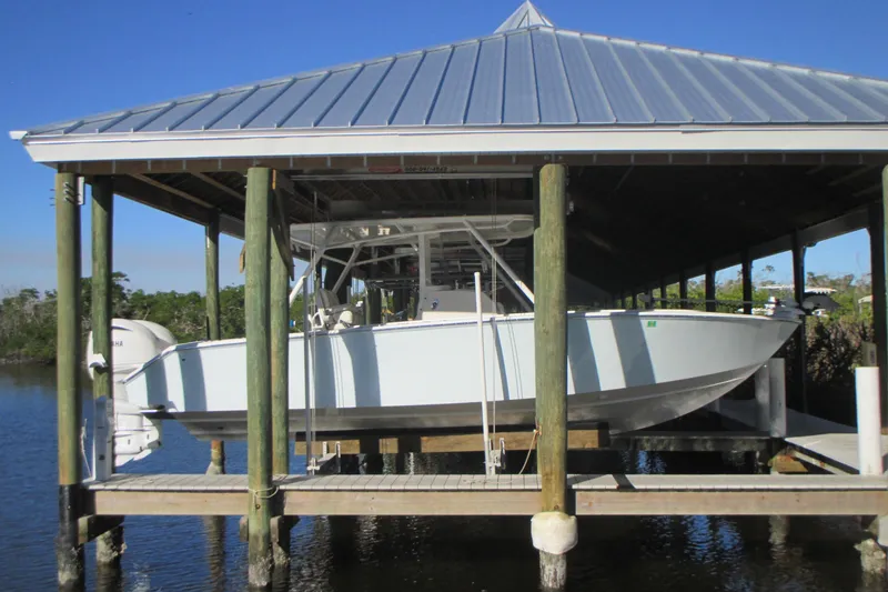 Slide: The Image of 2012 Jupiter 30 FS boat docked under a covered boathouse on a sunny day. - 2