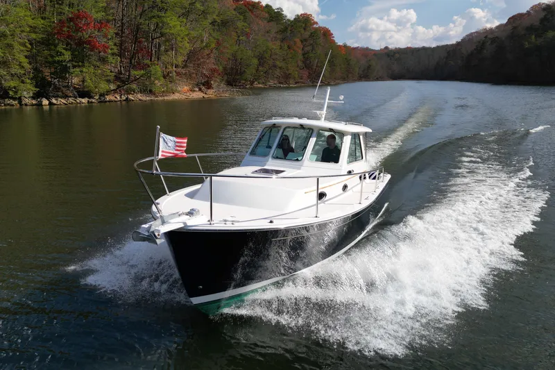 Slide: The Image of 2008 Back Cove 29 boat cruising on a scenic river with lush forest backdrop. - 12