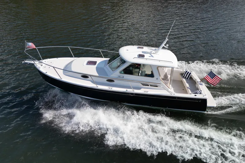 Slide: The Image of 2008 Back Cove 29 boat cruising on water with American flags displayed. - 13