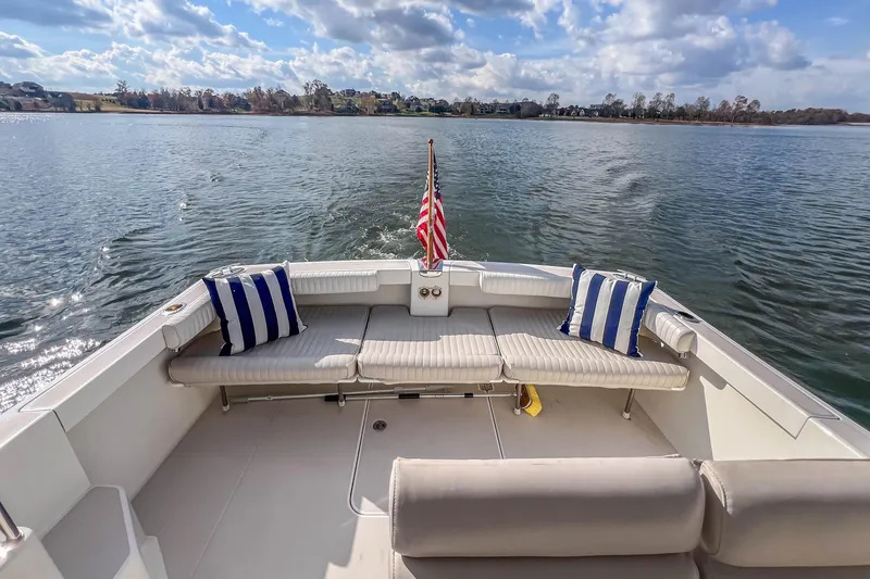 Slide: The Image of 2008 Back Cove 29 boat with striped cushions, American flag, on calm water under blue sky. - 23