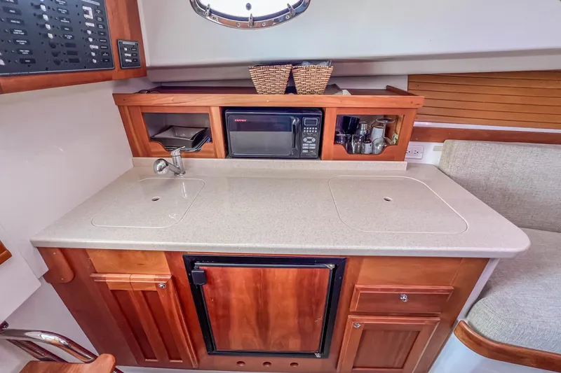 Slide: The Image of 2008 Back Cove 29 boat galley with sink, microwave, and storage cabinets. - 26