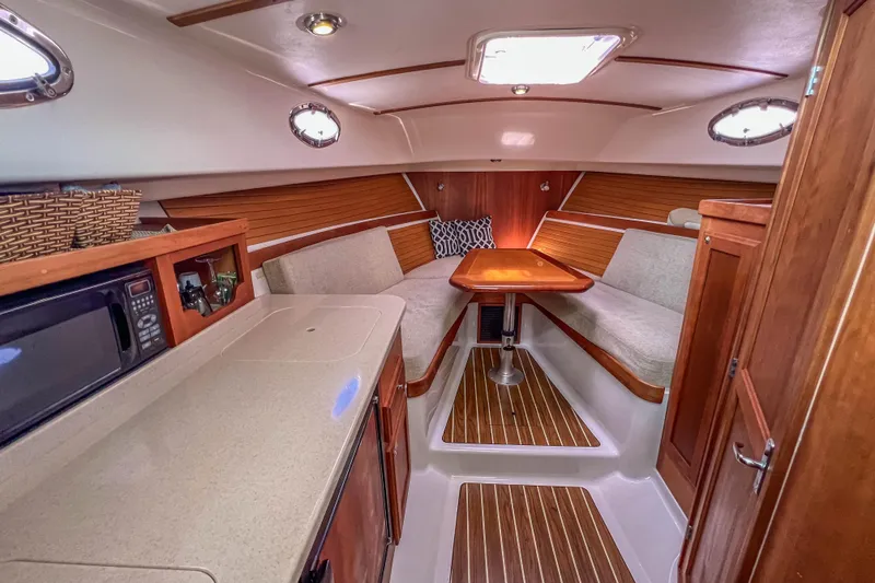 Slide: The Image of 2008 Back Cove 29 interior with cozy seating, wooden accents, and a compact kitchenette. - 30