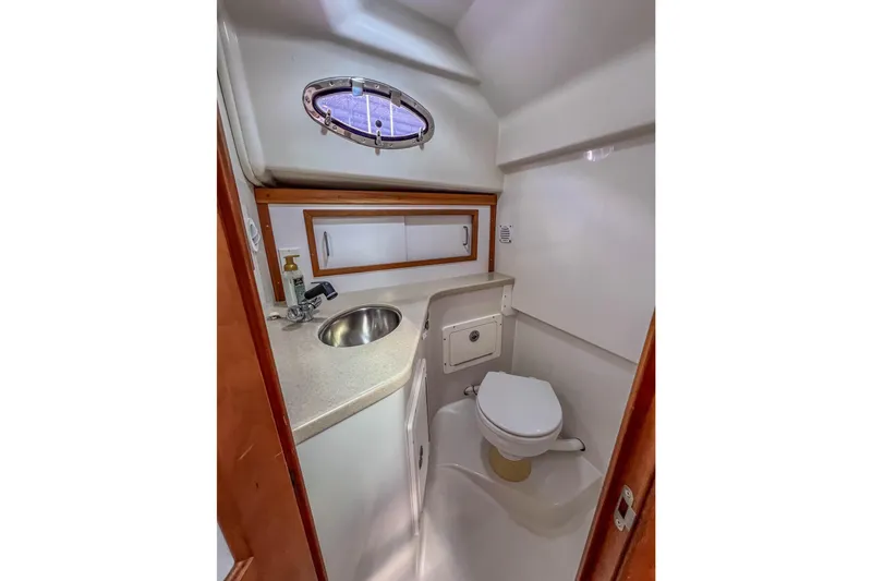 Slide: The Image of 2008 Back Cove 29 boat bathroom with sink, toilet, and porthole window. - 31