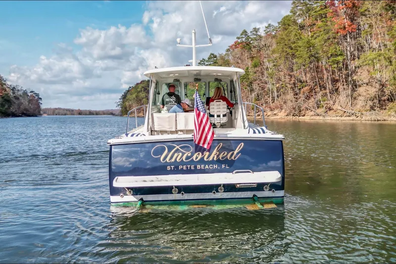 Slide: The Image of 2008 Back Cove 29 boat "Uncorked" cruising on a scenic lake with American flag. - 34