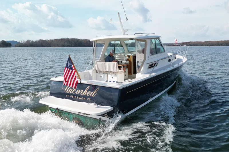 Slide: The Image of 2008 Back Cove 29 boat cruising on water with American flags, featuring sleek design and spacious cabin. - 4