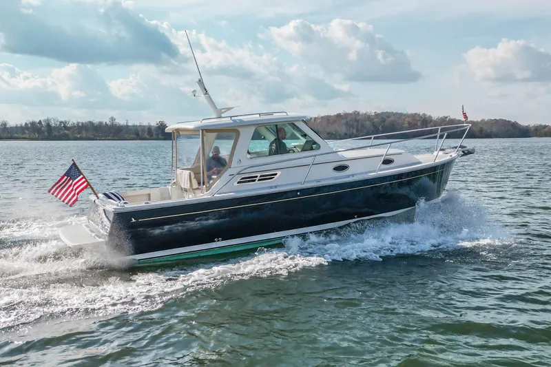 Slide: The Image of 2008 Back Cove 29 boat cruising on a lake with American flag, under a partly cloudy sky. - 8