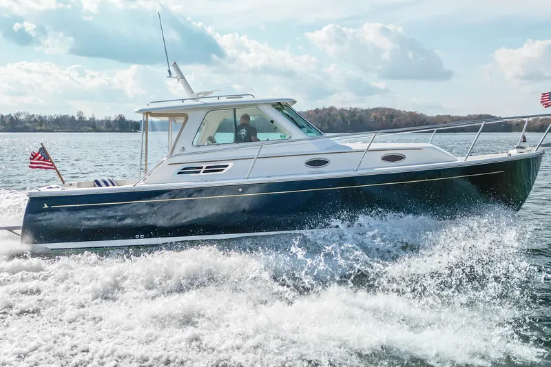 Slide: The Image of 2008 Back Cove 29 boat cruising on a sunny day with American flags. - 9