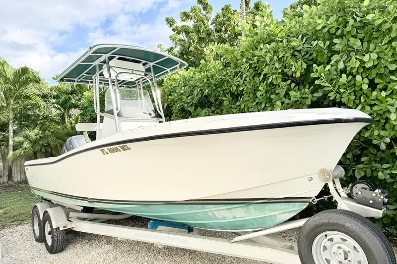 Slide: The Image of 2003 Custom 23 Center Console boat on trailer, surrounded by lush greenery. - 4