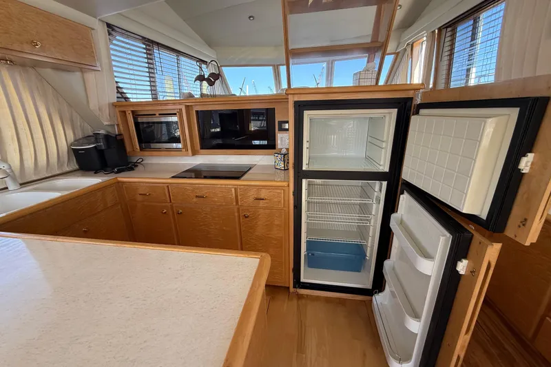 Slide: The Image of Kitchen area of 1999 Navigator 5300 yacht with open fridge and wooden cabinetry. - 21