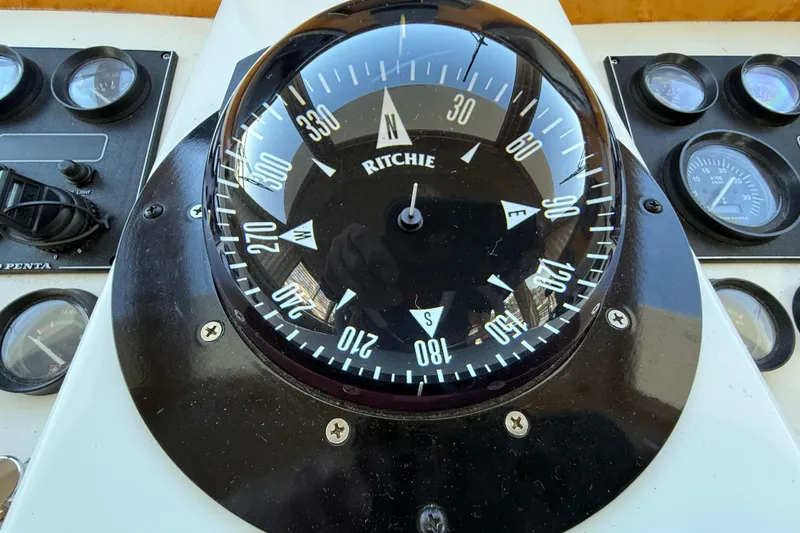 Slide: The Image of Compass and gauges on a 1999 Navigator 5300 boat dashboard. - 27