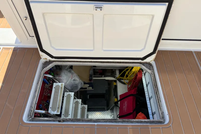 Slide: The Image of Open hatch on 1999 Navigator 5300 boat, revealing storage area with tools and equipment. - 69