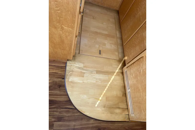 Slide: The Image of Wooden interior flooring of a 1999 Navigator 5300 yacht, featuring a hatch and cabinets. - 96