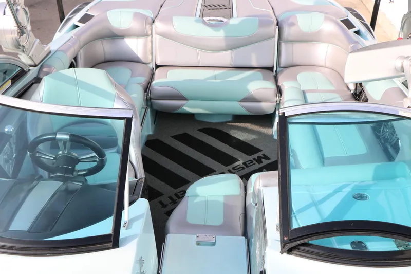 Slide: The Image of 2014 Master Craft X-Star boat interior with aqua and gray seating, featuring a sleek steering wheel. - 17